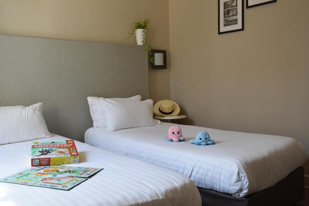 two beds with books and a hat on top of them at Hôtel Amirauté in Toulon