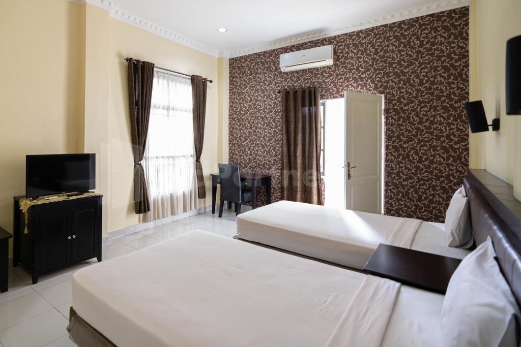 una camera d'albergo con due letti e una televisione di Carolina Transit Medan Mitra RedDoorz a Medan