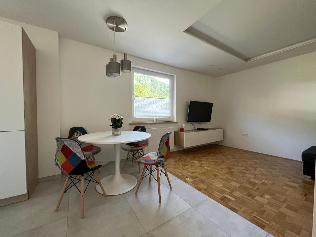 ein Wohnzimmer mit einem Tisch, Stühlen und einem TV in der Unterkunft Pod Galetovcem in Bohinjska Bela