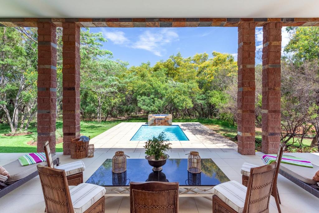 an outdoor patio with a table and chairs and a pool at Lejwe La Metsi Self-Catering Villa in Bela-Bela