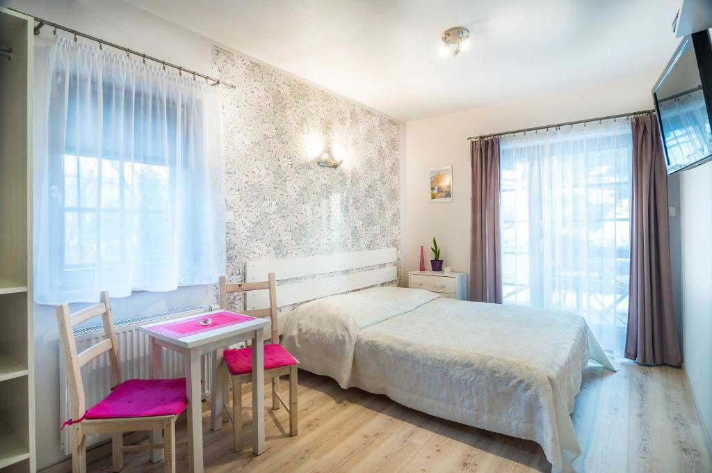 een slaapkamer met een bed en een tafel en stoelen bij Willa 4 Pory Roku in Kazimierz Dolny