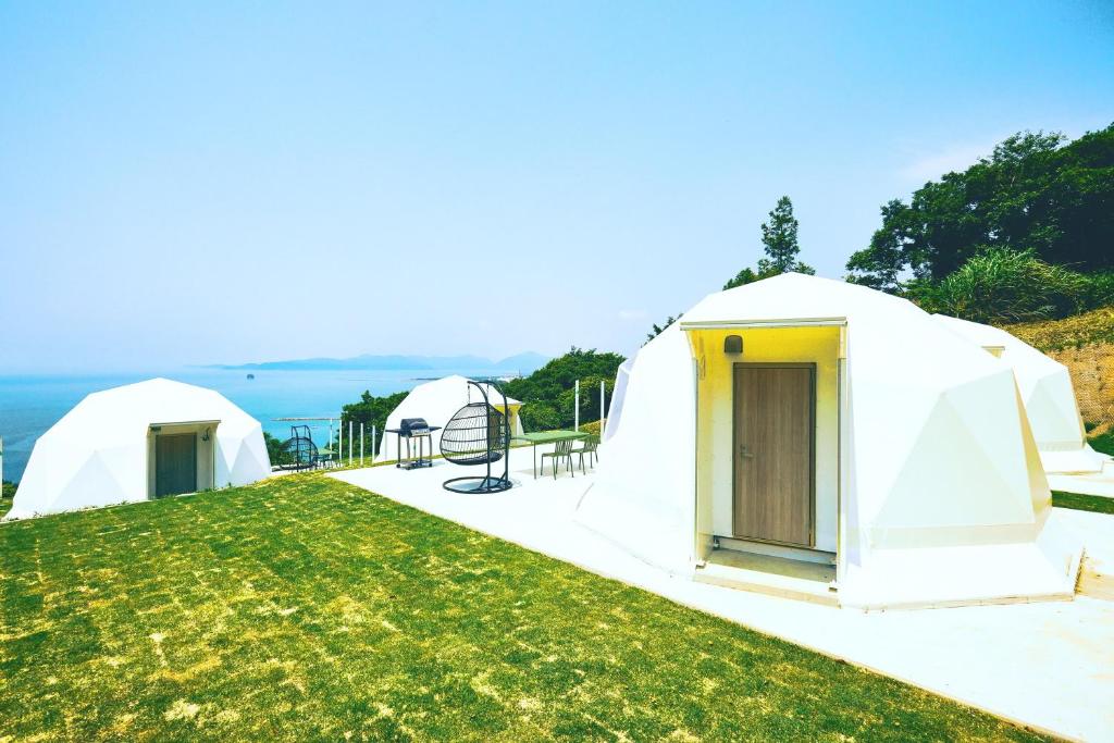 a group of tents in a field with the ocean at Dot Glamping 赤穂 in Ako