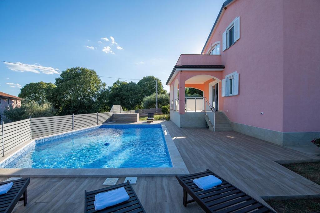 a swimming pool next to a pink house at Apartment Mariuccia with Private Pool in Vrsar