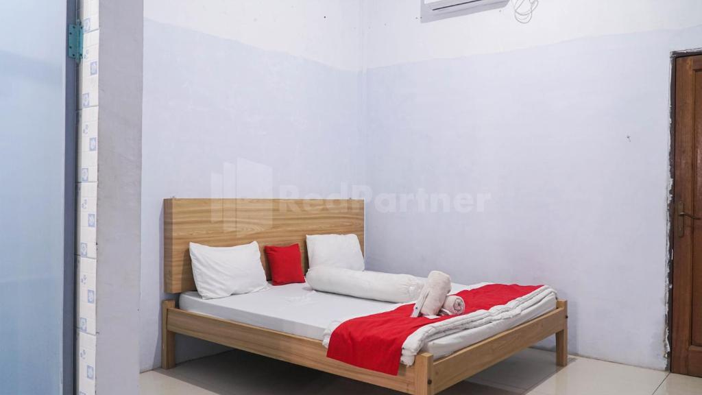 uma cama com um cobertor vermelho e almofadas brancas em The Karo's Residence Mitra RedDoorz em Sunggal