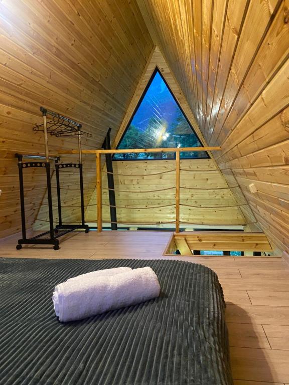 a bed in a wooden room with a window at Labna Huts in Mestia