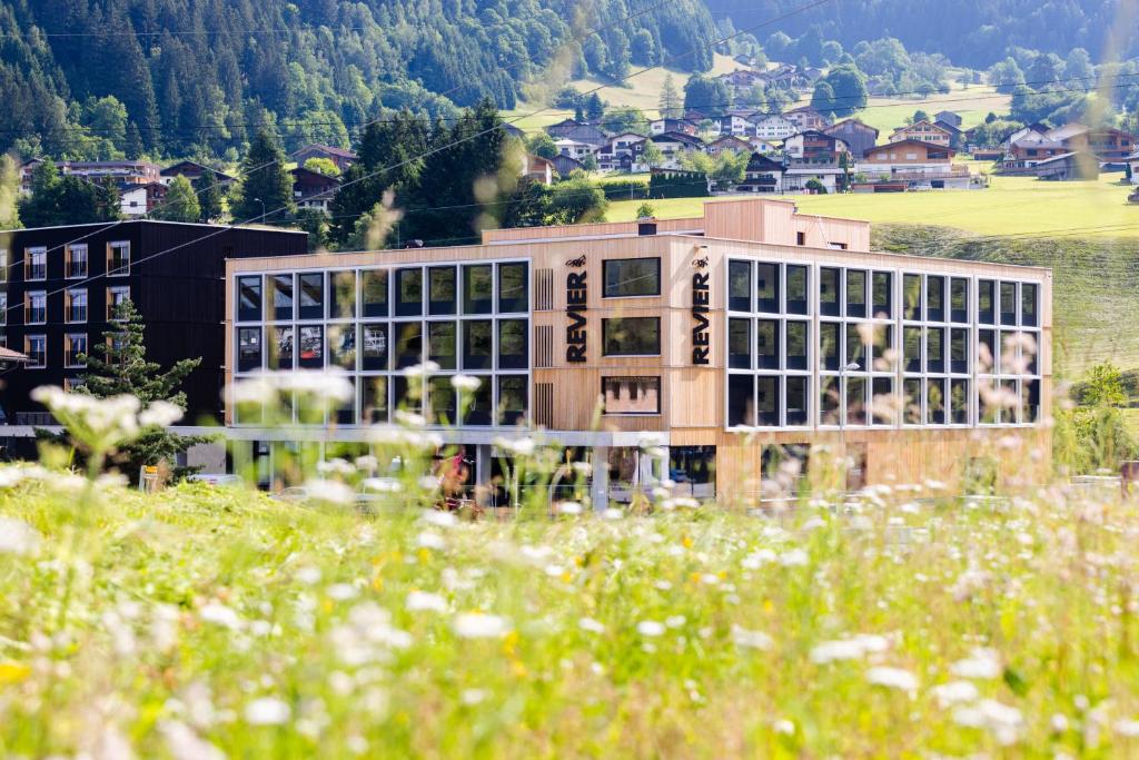 un gran edificio con ventanas en un campo de flores en Revier Mountain Lodge Montafon, en Sankt Gallenkirch