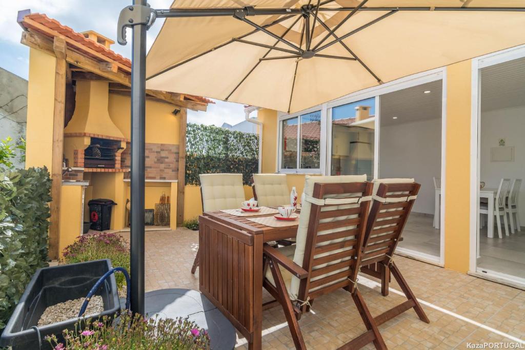 einen Holztisch und Stühle unter einem Sonnenschirm auf einer Terrasse in der Unterkunft Santa Catarina Terrace in Estoril