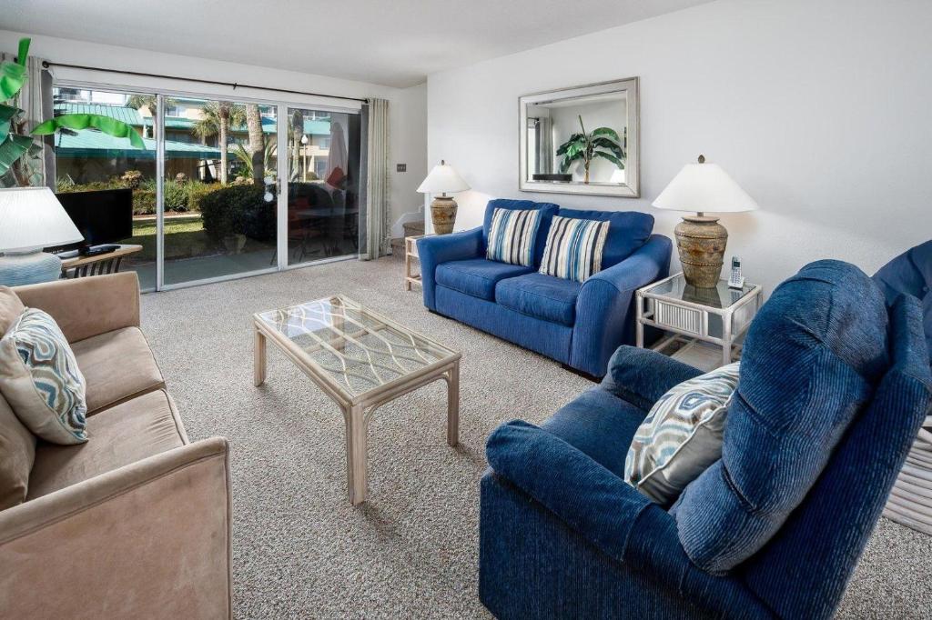 - un salon avec des canapés bleus et une table dans l'établissement Seaspray Condos 107B, à Fort Walton Beach