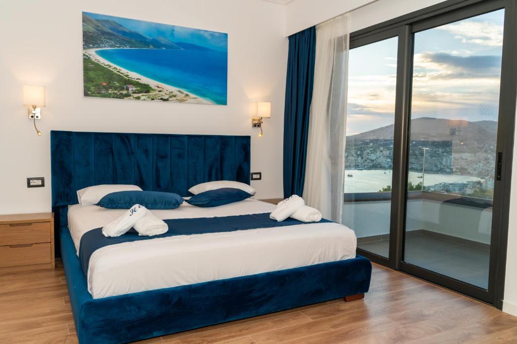 a bedroom with a bed and a large window at Hilltop Heaven Hotel in Sarandë