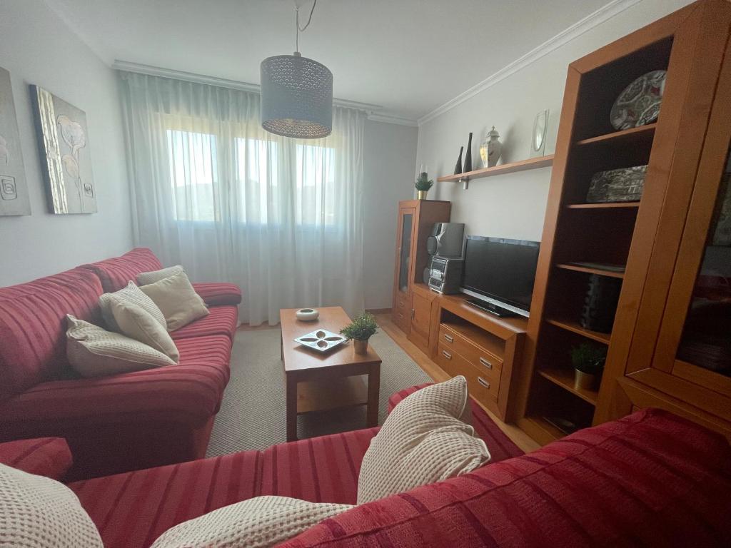 sala de estar con sofá rojo y TV en Apartamento en Viveiro con aparcamiento gratuito, en Viveiro