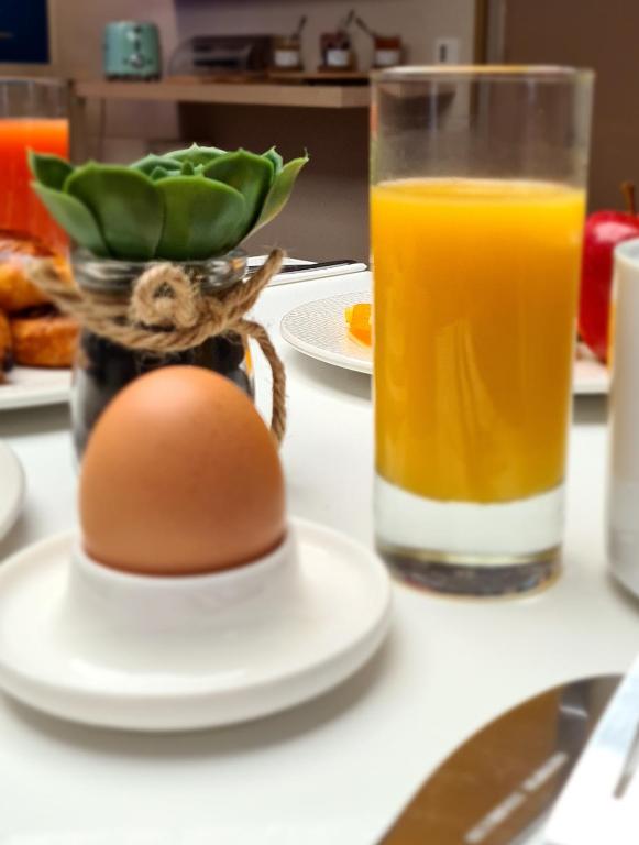 a glass of orange juice and an egg on a table at Hôtel Amirauté in Toulon