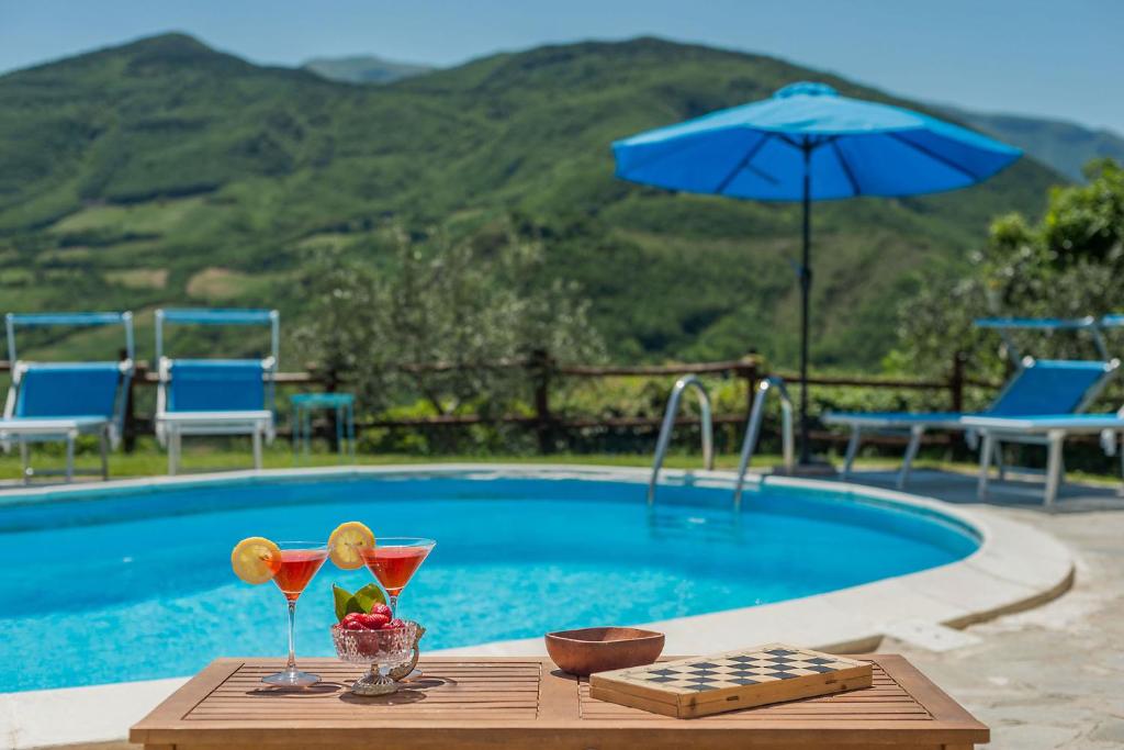uma mesa com duas bebidas ao lado de uma piscina em Villa Colombaia em Acqualagna