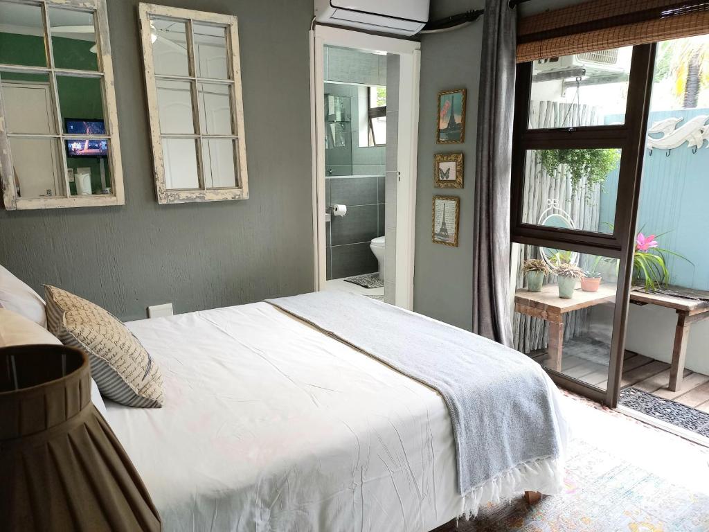 a bedroom with a white bed and a bathroom at Driftwood Suite, Villa Roc Guesthouse , Ballito, Salt Rock- No loadshedding in Sheffield Beach