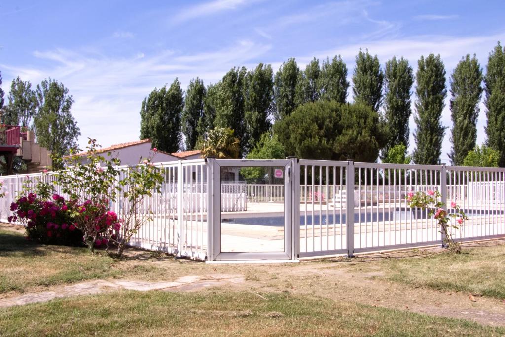 una cerca blanca con una puerta en un patio en Le Marais - Village Vacances, en Meschers-sur-Gironde