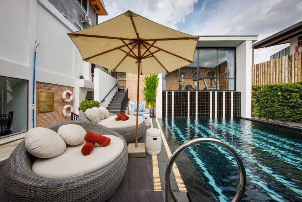 a house with a swimming pool with two beds and an umbrella at Chala Number 2 Art and Gallery in Chiang Mai