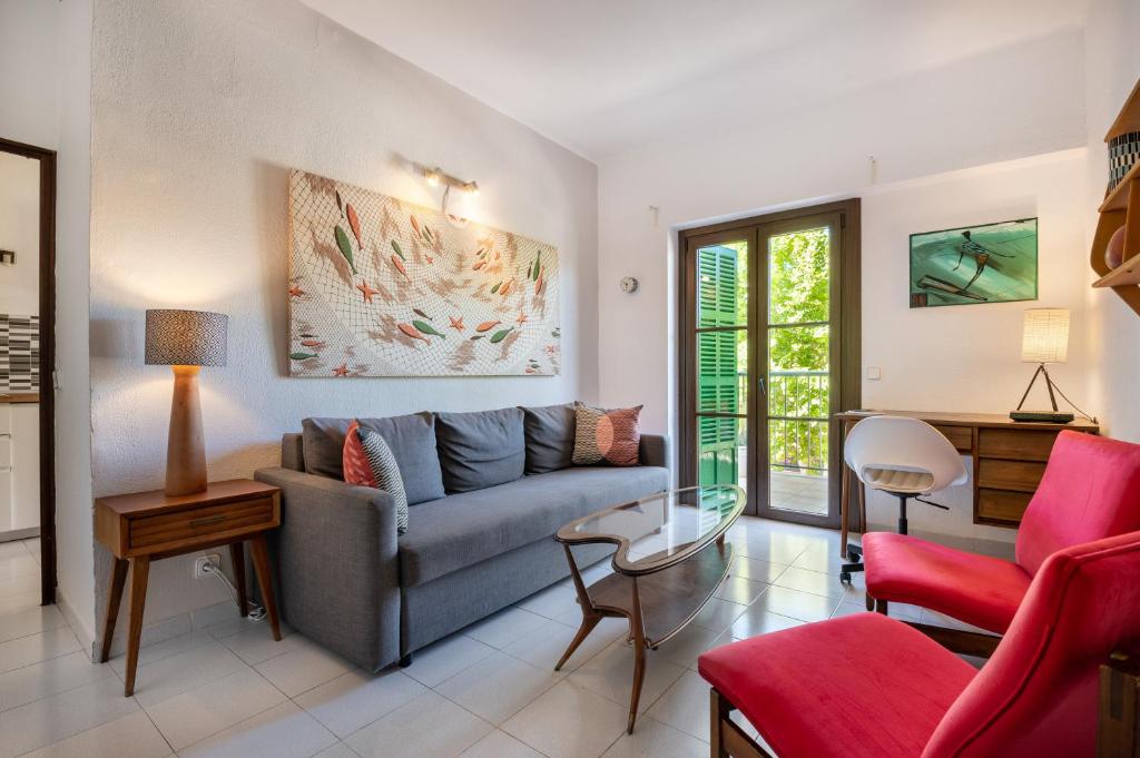 sala de estar con sofá gris y sillas rojas en Seafront Apartment in Port Sóller, en Puerto de Sóller