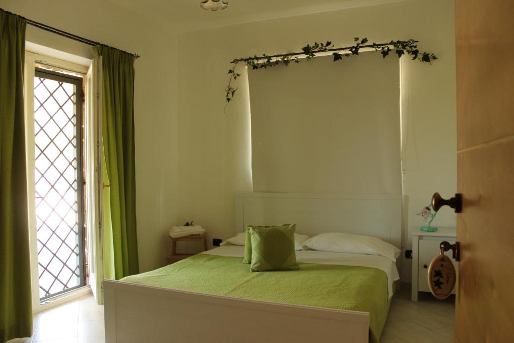 Un dormitorio con una cama con sábanas verdes y una ventana en Le Rocce en SantʼAgata deʼ Goti