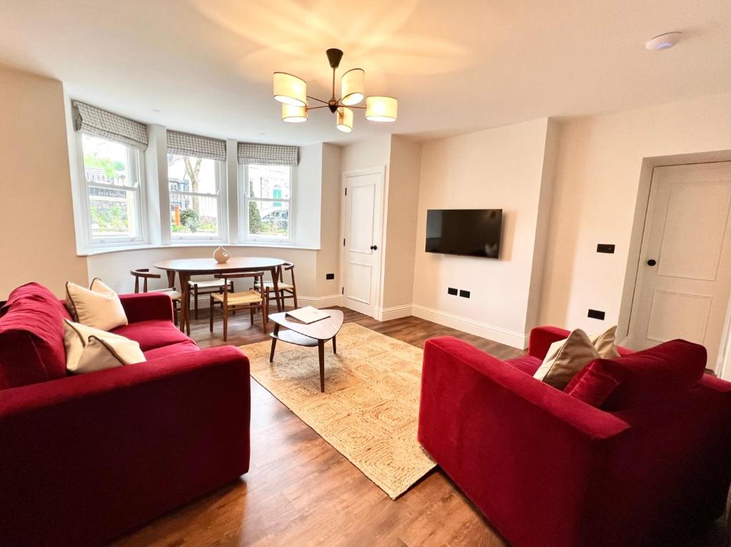 ein Wohnzimmer mit zwei roten Sofas und einem Tisch in der Unterkunft Redland Suites - Apartment 2 in Bristol
