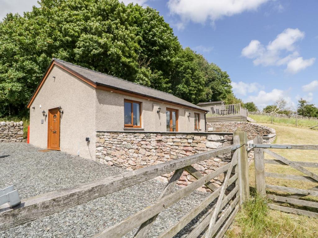 a stone cottage with a wooden fence next to it at Little Barn in Grange Over Sands