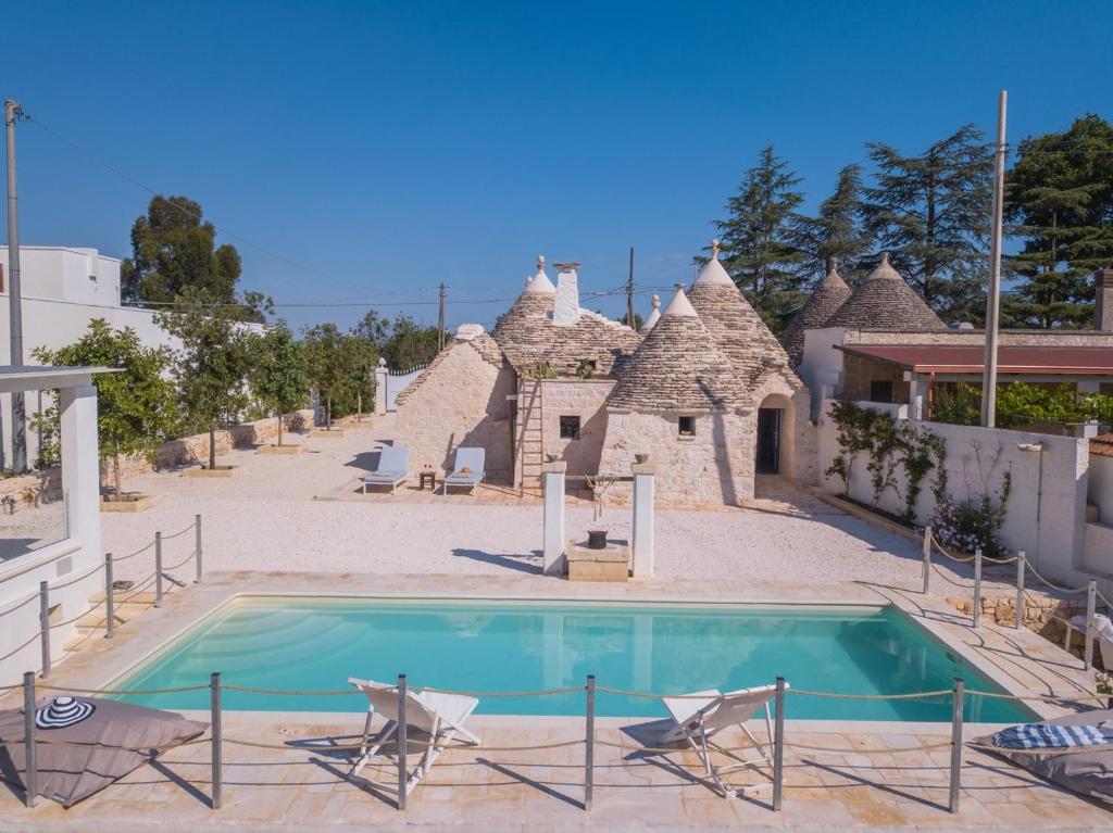 una piscina di fronte a una casa con sedie di HelloApulia - Authentic Trulli Petricore with private SPA and pool a Monopoli