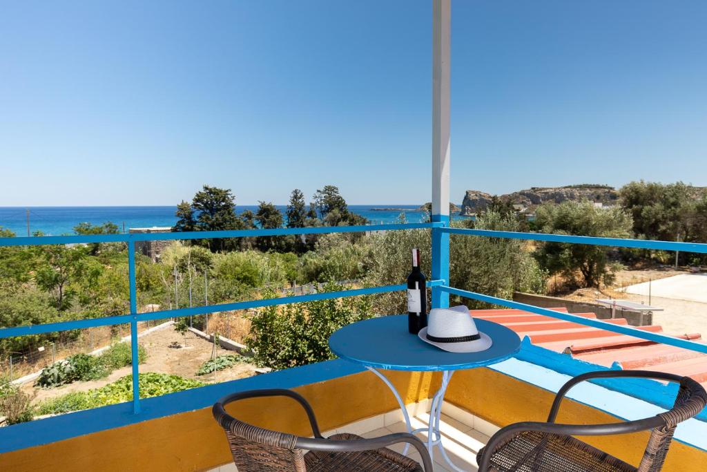 een balkon met een blauwe tafel en stoelen en de oceaan bij Plastiras Sea View Apartments in Archangelos