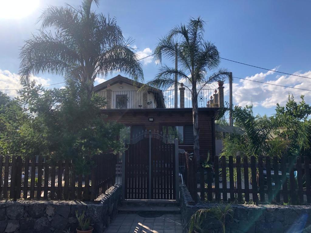 une maison avec un portail et une clôture avec des palmiers dans l'établissement Villetta Due Palme - vicino GIARDINI NAXOS -, à Calatabiano