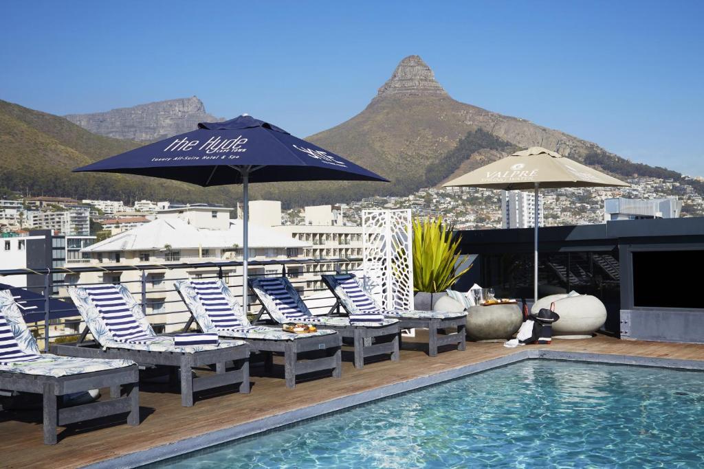 a pool with chairs and umbrellas on a rooftop at The Hyde All Suite Hotel in Cape Town