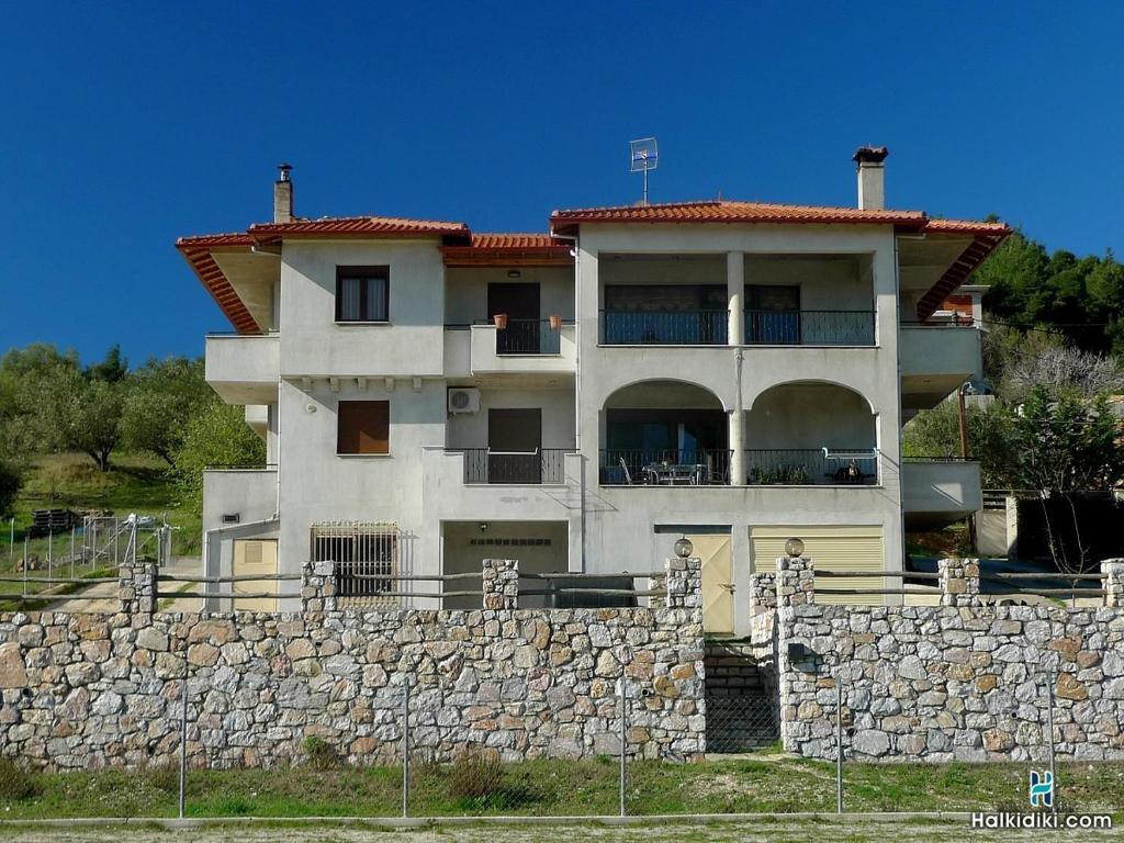 a large white house with a stone wall at Village view apartment in Ayios Nikolaos Sithonia