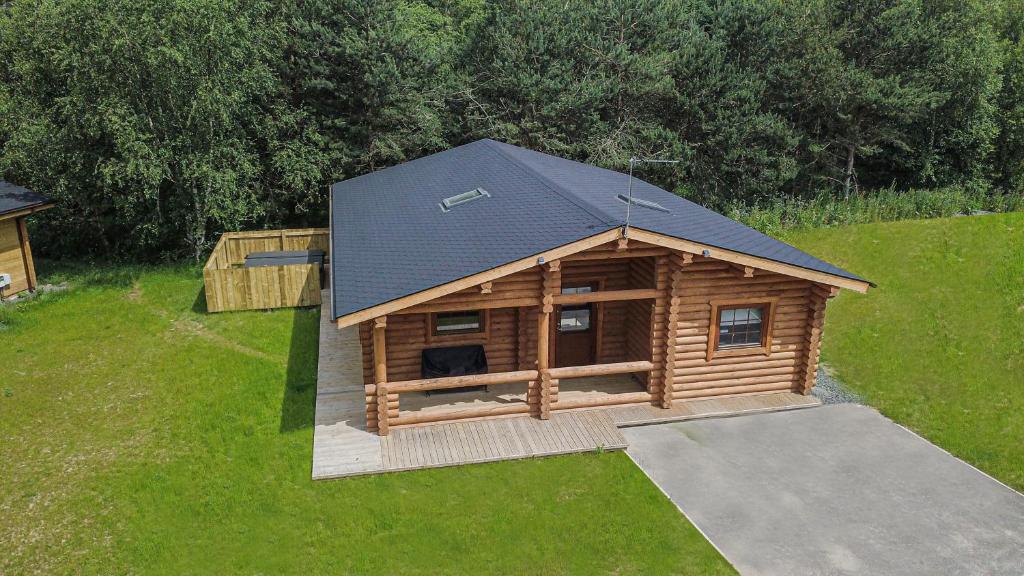 a log cabin with a black roof on a yard at Aspen Lodge, Amazing New Log Cabin with Hot Tub - Sleeps 6 - Felmoor Park in Morpeth