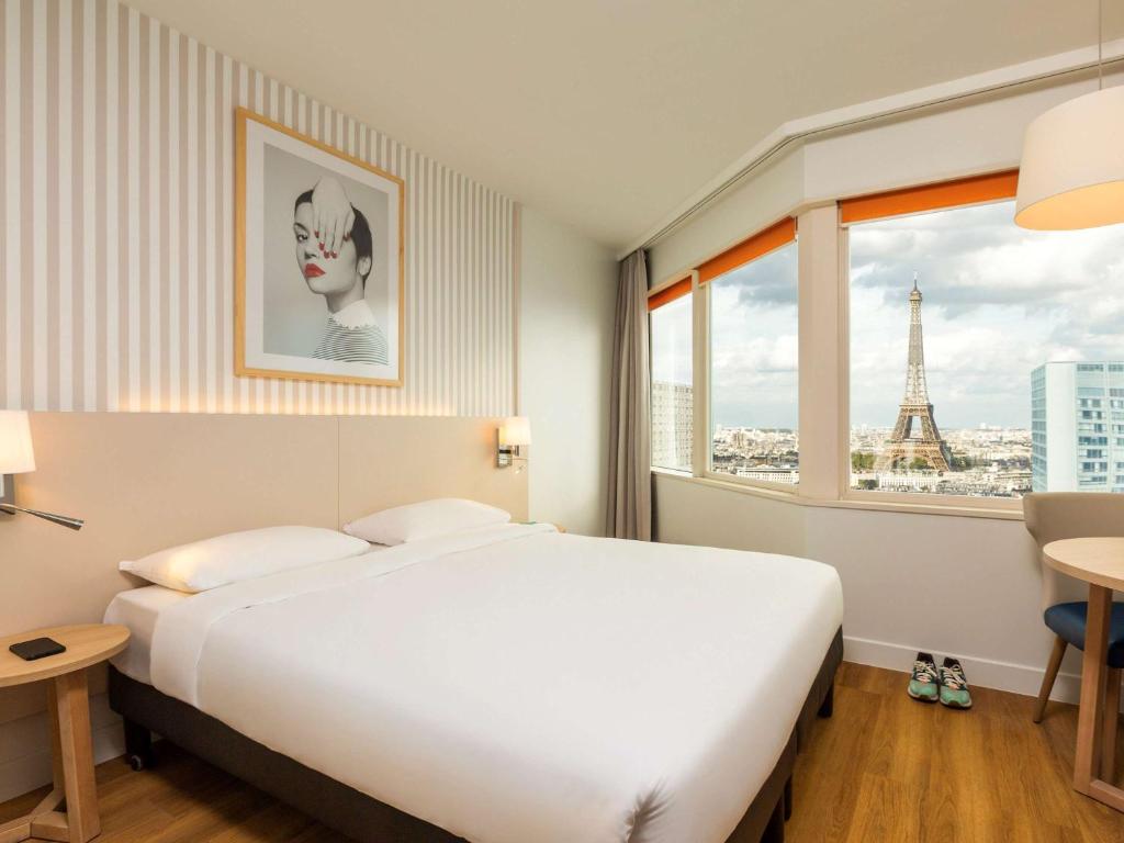 パリにあるアパートホテル アダージョ パリ センター トゥール エッフェルのベッドルーム1室(ベッド1台付)、エッフェル塔のある窓が備わります。
