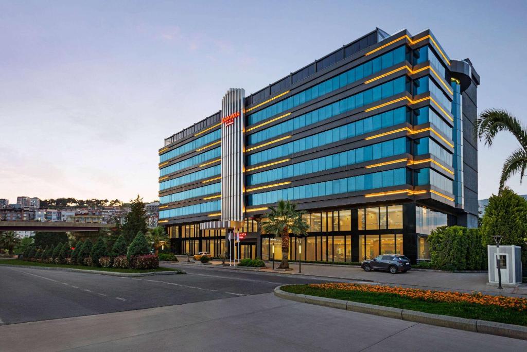 un gran edificio de oficinas con un coche aparcado delante de él en Ramada Plaza by Wyndham Samsun en Samsun