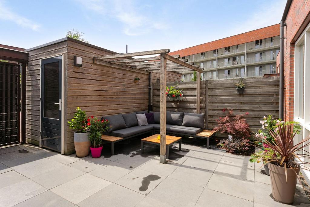 een patio met een bank en een pergola bij Residence Sanne in Breda