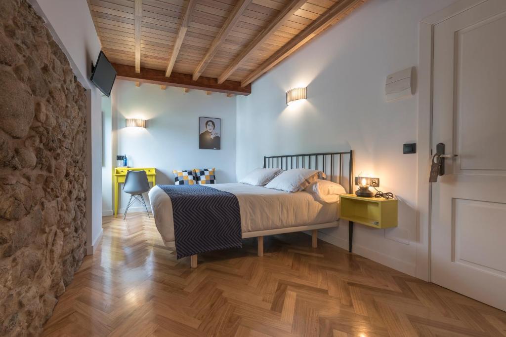 a bedroom with a bed and a stone wall at Lugar das Marías in Jove