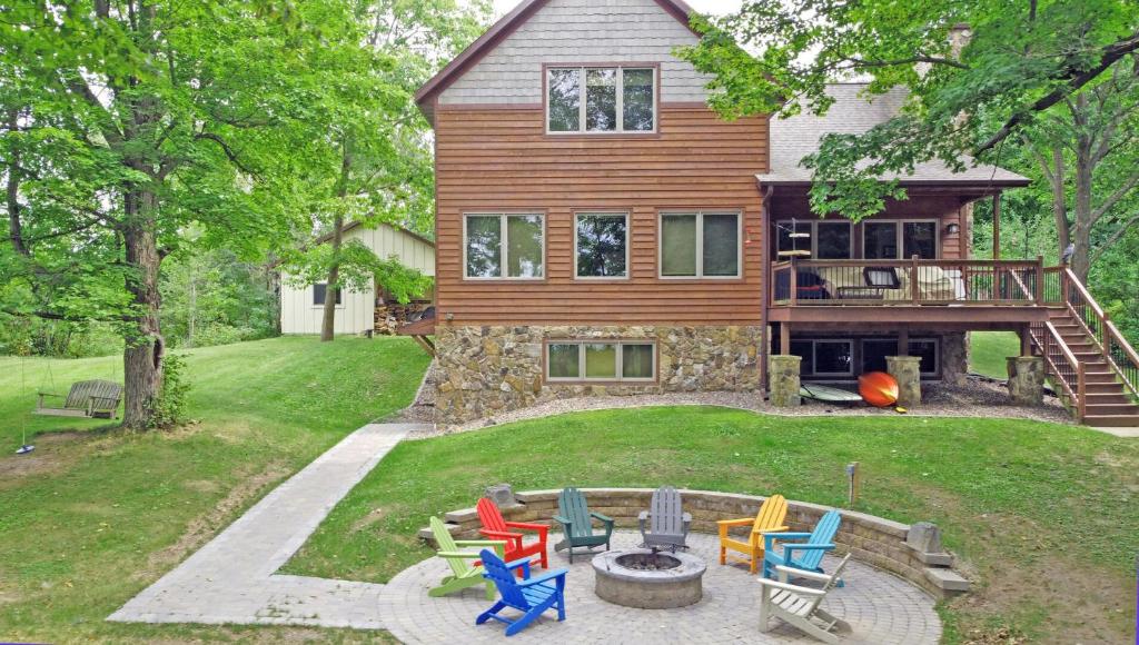 Cette maison dispose d'une terrasse avec des chaises colorées dans la cour. dans l'établissement Ravensong Lodge, à New Auburn