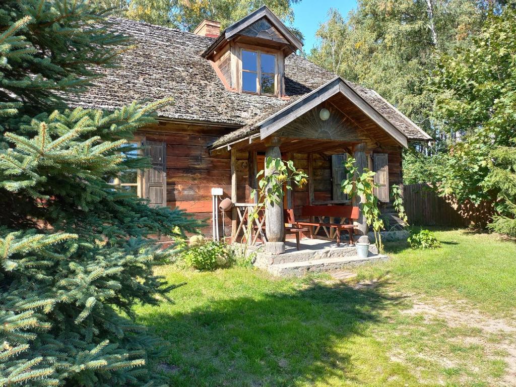 a log cabin with a porch in a yard at Chata Kurpiowska in Nowogród