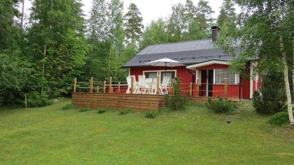 une maison rouge avec une terrasse dans une cour dans l'établissement Mannimaatila Uni Lux, à Punkaharju