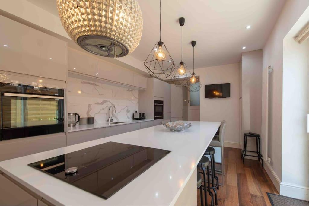 a large kitchen with a large white counter top at Large Townhouse Penarth, Cardiff in Cardiff