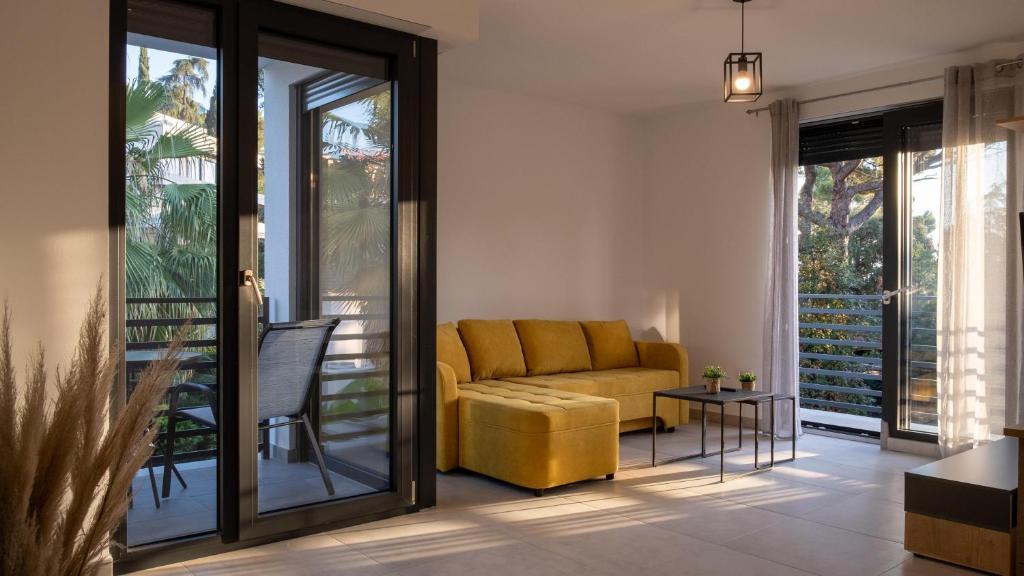 salon z żółtą kanapą i przesuwnymi szklanymi drzwiami w obiekcie Apartments Katarina w Rovinj