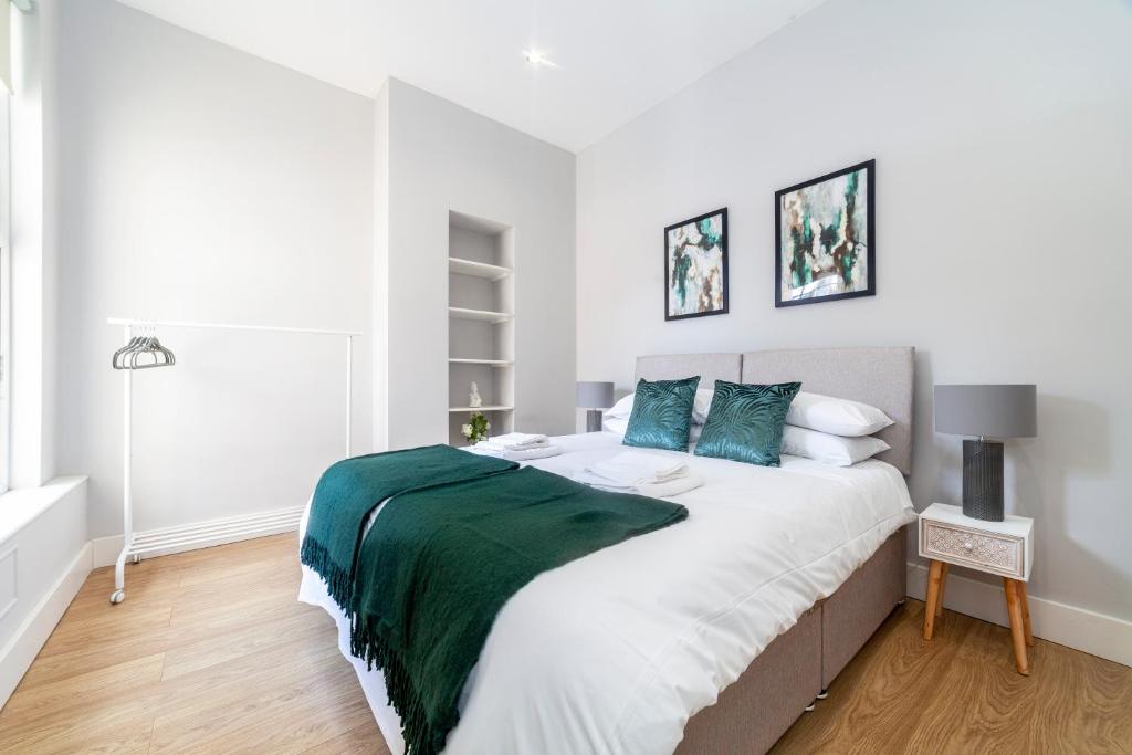 een witte slaapkamer met een groot bed met blauwe kussens bij West Kensington in Londen