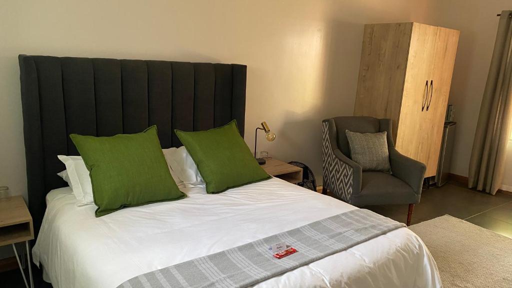 a bedroom with a bed with green pillows and a chair at The Chameleon Stay @107 in Centurion