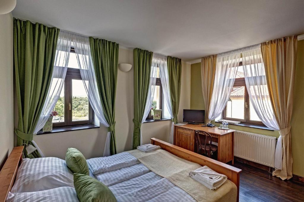 a bedroom with two beds and a television and windows at Hotel Buchlov in Buchlovice