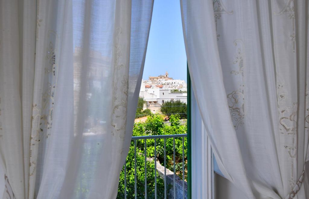 Aussicht aus einem Fenster mit weißen Vorhängen in der Unterkunft Palazzo Greco - Luxury Apartments with sea-view in Ostuni