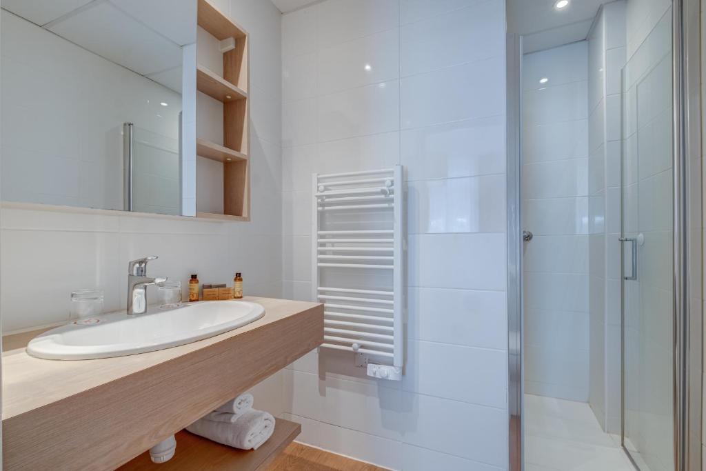 a white bathroom with a sink and a shower at Hôtel Miléade L'Orangeraie - Menton in Menton