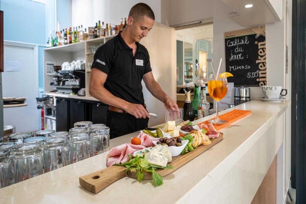 a man standing in a kitchen preparing food at Hôtel Miléade L'Orangeraie - Menton in Menton