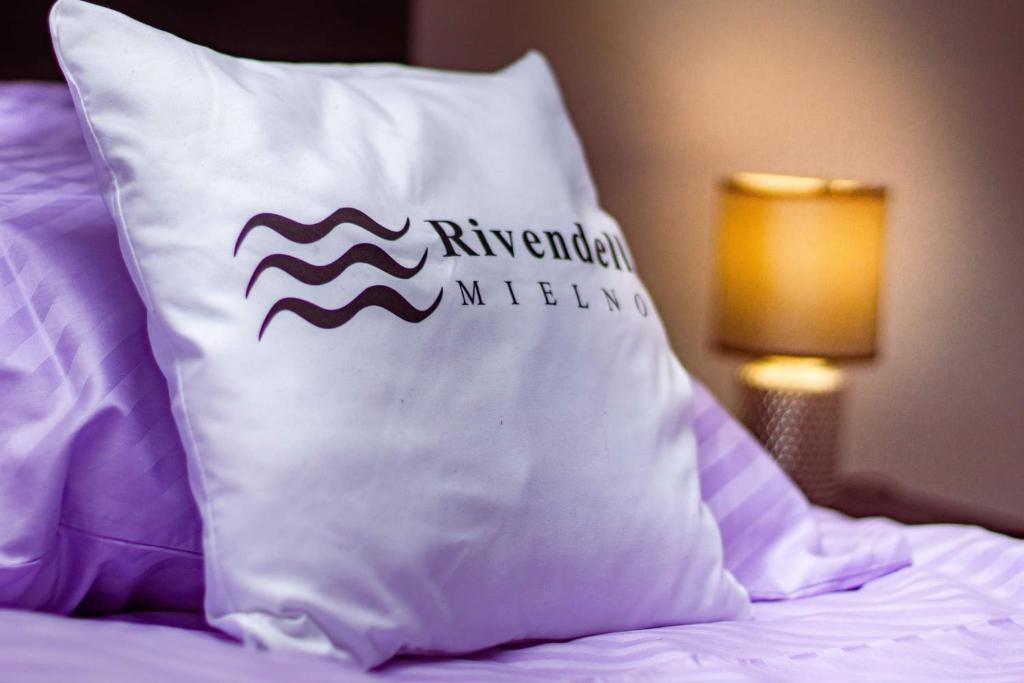 una almohada sobre una cama junto a una lámpara en Rivendell Mielno, en Mielno