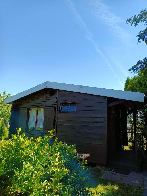 a small wooden house with a tin roof at SŁONECZNIK domki letniskowe Charbrowo-Łeba in Charbrowo