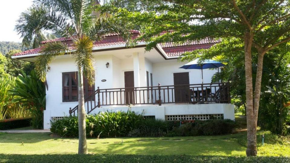 a white house with a balcony with an umbrella at Sunflower Villas in Ko Chang