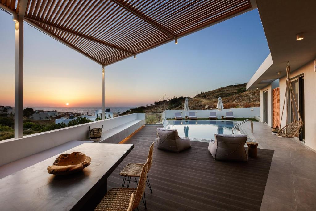 una terraza al aire libre con mesa, sillas y piscina en Sueno Villas en Panormos Rethymno