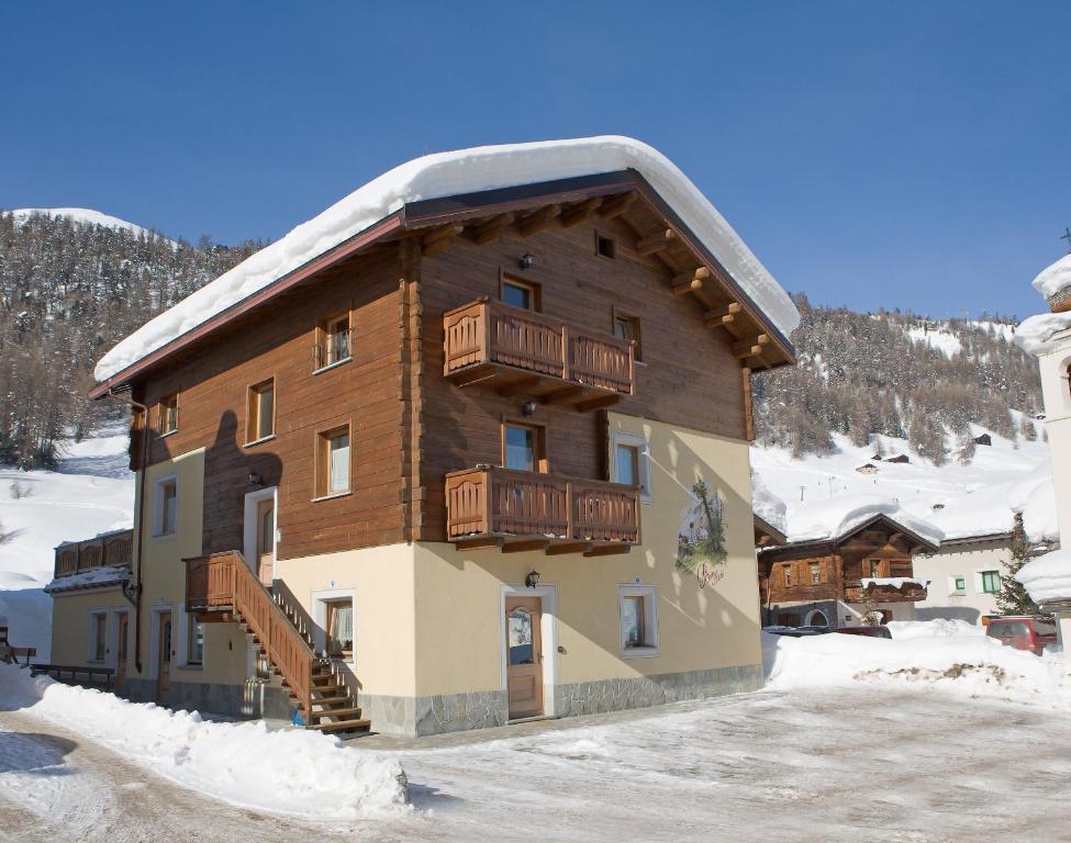 ein großes Holzgebäude mit Schnee auf dem Boden in der Unterkunft Baita Aris Appartamento Canton in Livigno