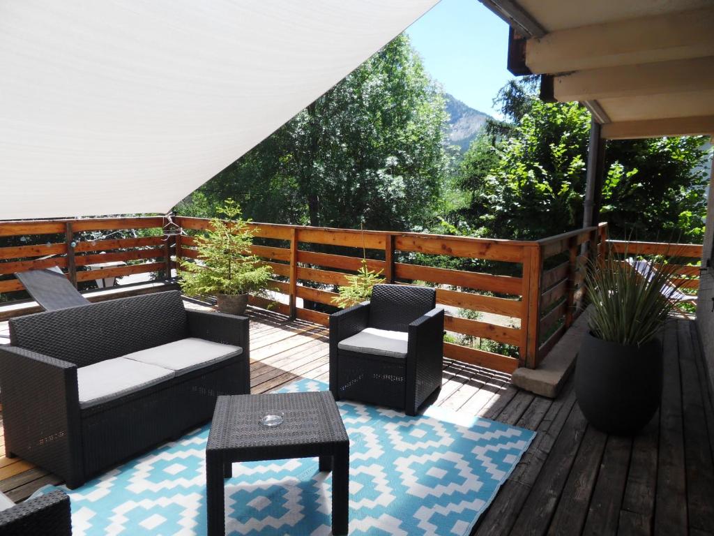 a deck with furniture and a view of a mountain at Hôtel du Verdon in Beauvezer